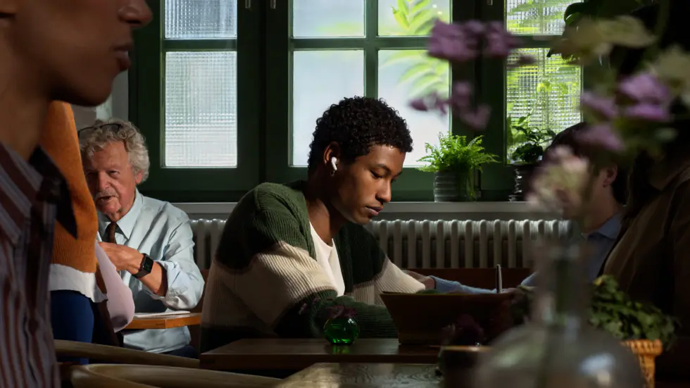 A person wearing AirPods 5, focused in a busy café