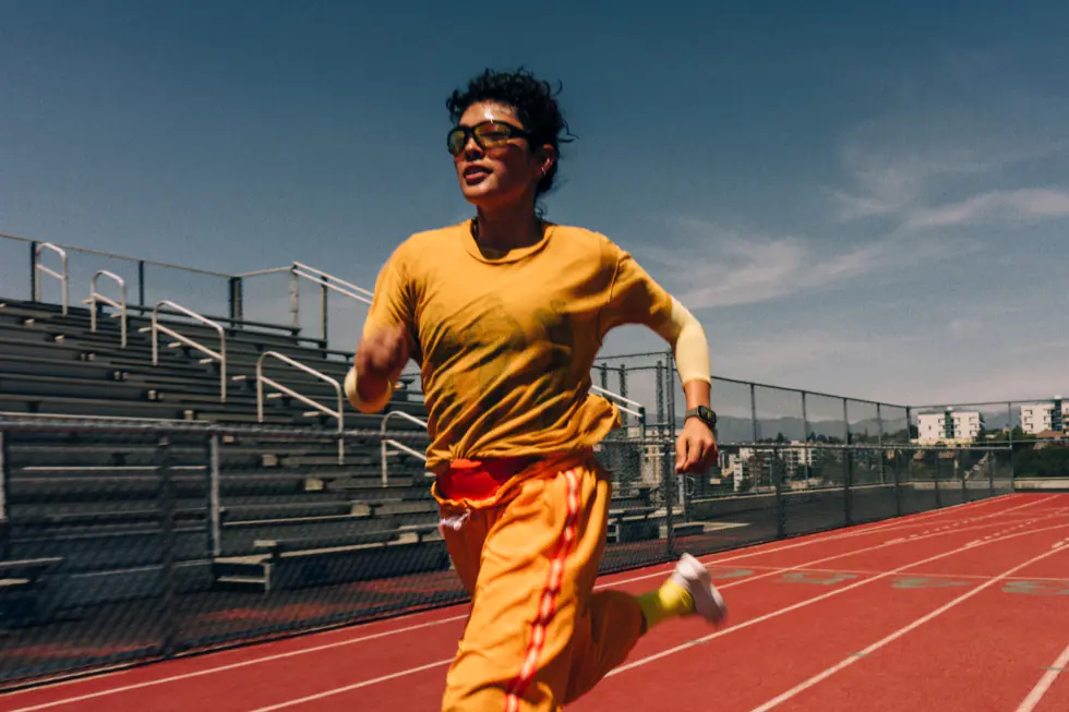 A person running on an athletics track, wearing Apple Watch